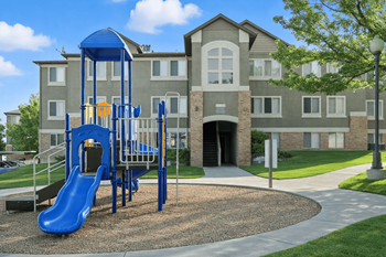 A playground with a blue slide in front of a building.